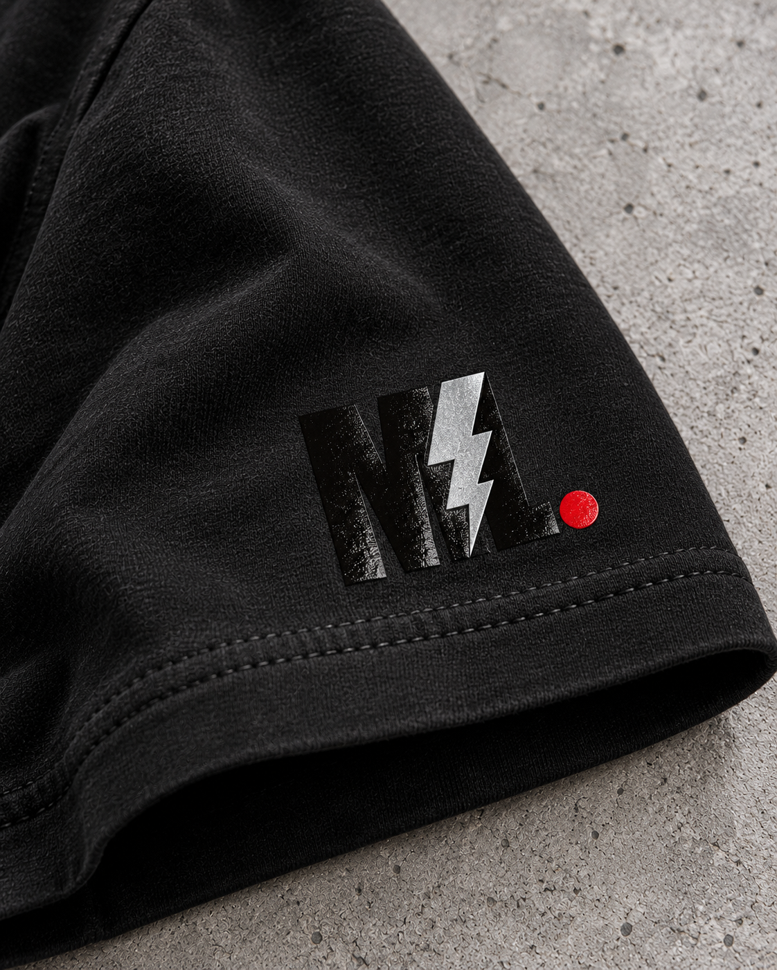 Close-up of glossy black-on-black ML sleeve logo, reflective silver lightning bolt and red period.