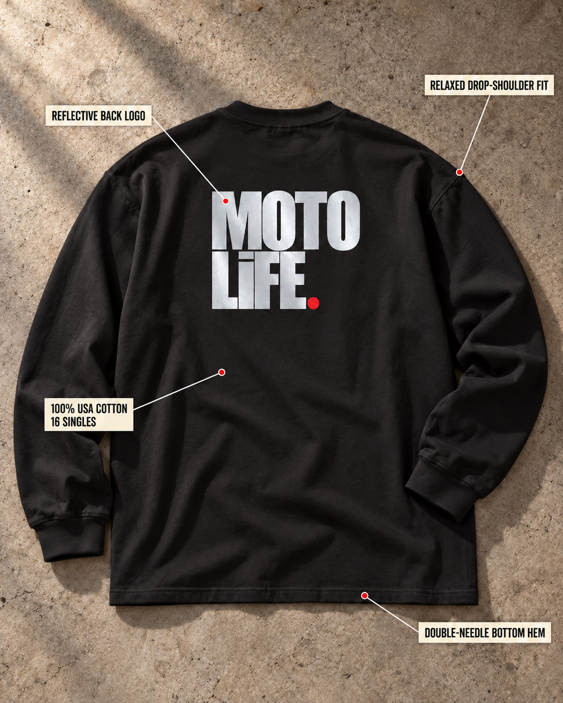MOTOLiFE V2 black long-sleeve T-shirt back flat lay on concrete. Callouts identify the reflective back logo, relaxed drop-shoulder fit, 100% USA cotton with 16 singles and double-needle bottom hem.